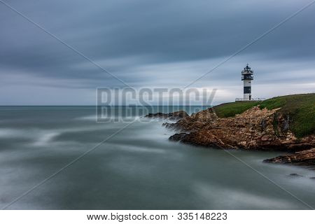 Lighthouse At Sunset With Cloudy Sky And Clear Horizon, Long Exposure