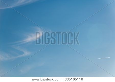 A Beautiful Blue Sky With Whispy Clouds And An Aeroplane In The Distance