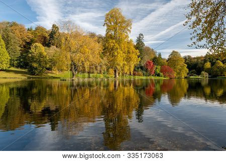 View Of The Autumn Colours Around The Lake At Stourhead Gardens In Wiltshire.