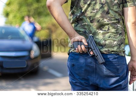 Aggressive Driver With Gun Hidden In The Back. Concept Of Violence In Traffic. Person With Gun In Tr