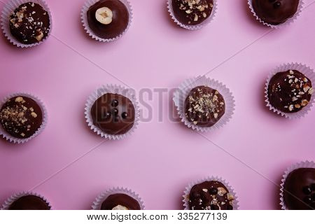 Chocolate Candies In Paper Tartlets On A Pink Background. View From Above. Flat Lay.
