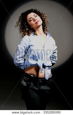 Girl With Curly Hair In A Beam Of Bright Light (gobo Mask) In A Linen Blue Shirt On A White Backgrou