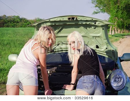 Twee Sexy Blonde meisjes staan door de gebroken auto. Achteraanzicht