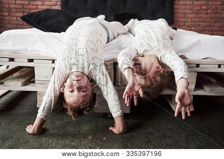 Happy Kids Playing In Black Bedroom. Little Boy And Girl, Brother And Sister Play On The Bed Wearing