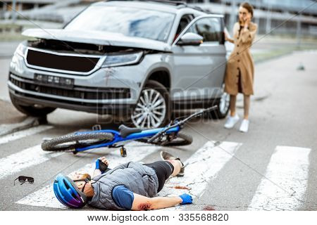 Road Accident With Injured Cyclist Lying On The Pedestrian Crossing Near The Broken Bicycle And Worr