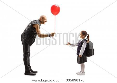Full length shot of a punker in leather clothes giving a red baloon to a schoolgirl isolated on white background