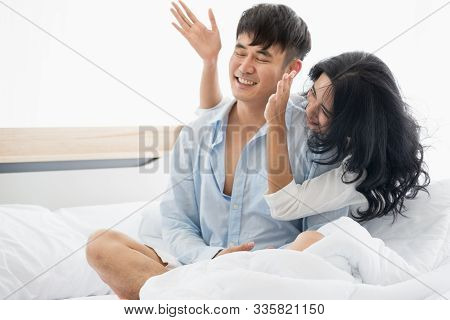 Asian Couple Sitting On The Bed Together, Woman Blindfolded Boyfriend.