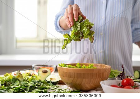 Pregnant Woman In Blue Shirt Prepares Vegetable Salad Of Spinach, Avocado, Cherry Tomatoes, Throws L