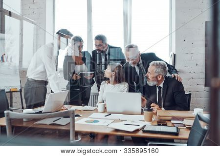 Self-driven Business Team Analyzing Sales Using Modern Technologies While Having Staff Meeting In Th