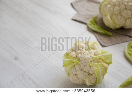 Raw Cauliflower Head On A White Wooden Background, Side View. Space For Text.