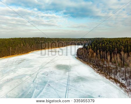 Beautiful Aerial View Of Ice Covered Balzis Lake. Snowy Pine Forests Surrounding A Small Lake. Sceni