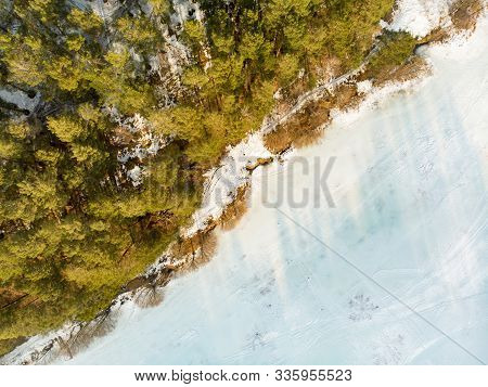 Beautiful Aerial View Of Ice Covered Balzis Lake. Snowy Pine Forests Surrounding A Small Lake. Sceni