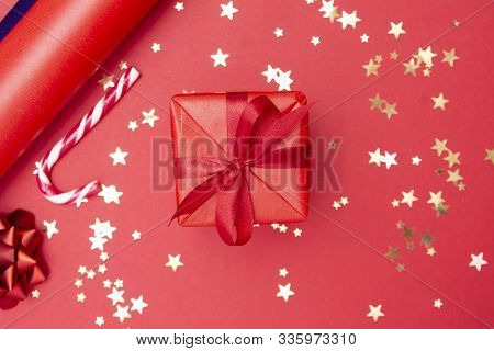 Christmas Background, Red Gift Box With Ribbon Bow On Red Background And Golden Sparkling Conffeti, 