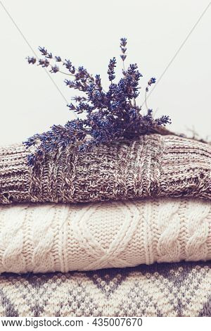Woolen Sweaters And Dried Lavender For Protection From Moth. Knitted Warm Wool Clothes. Stack Of War