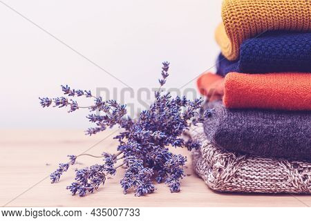 Woolen Sweaters And Dried Lavender For Protection From Moth. Knitted Warm Wool Clothes. Stack Of War