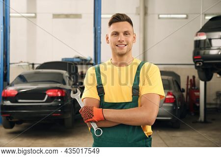 Portrait Of Professional Mechanic With Wrench At Automobile Repair Shop