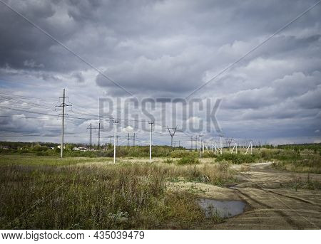 A Harsh Landscape - Power Transmission Towers Extending Into The Distance, A Pre-stormy Sky With Clo