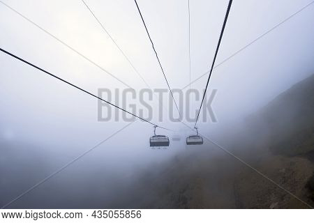 Cable Car In The Mountains With Clouds Or Fog. View From The Cable Car To The Mountain Landscape. Wi