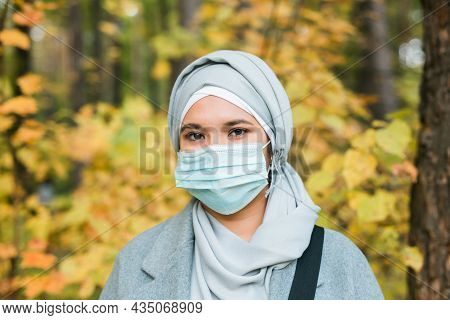 Muslim Woman With Hijab Is Wearing Face Mask Outdoors. Coronavirus, Health Care And Pandemic Concept