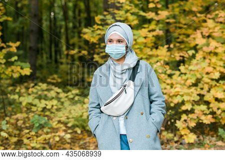 Muslim Woman With Hijab Is Wearing Face Mask Outdoors. Coronavirus, Health Care And Pandemic Concept