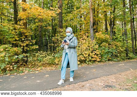 Muslim Woman With Hijab Is Wearing Face Mask Outdoors. Coronavirus, Health Care And Pandemic Concept