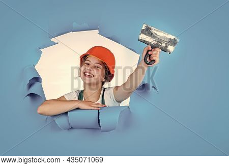 Builder In Coveralls And Helmet With Spatula. Kid Repair Wall With Spackling Paste. Home Renovation.
