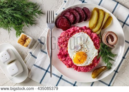Close-up Of Labskaus, Corned Beef, Mashed Potatoes With The Beetroot Topped With Fried Eggs, Sliced 
