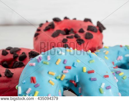 Red And Blue Cronuts On A White Wooden Background. High Quality Photo