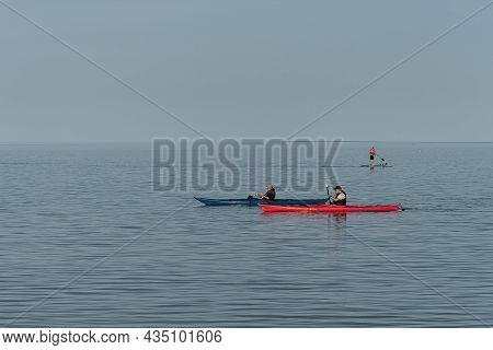 Two Old Men Paddeling Kayak On The Calm Sea And A Man On A Paddleboard In The Background, Vejle, Den