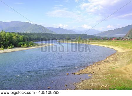 The Bank Of A Mountain River Under A Blue Cloudy Sky. Altai, Siberia, Russia