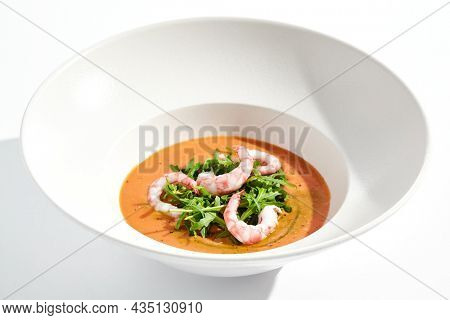 Summer Spanish soup gazpacho with shrimp and rocket salad isolated on white background. Healthy cold tomato soup with prawns. Clean eating for diet.Healthy food in restaurant menu. Seafood gazpacho