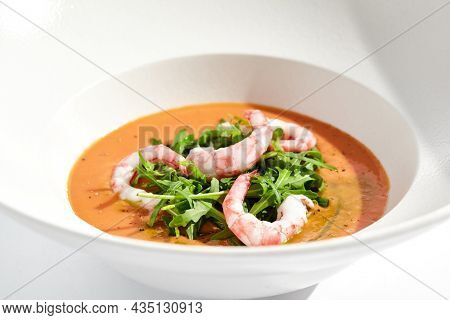 Summer Spanish soup gazpacho with shrimp and rocket salad isolated on white background. Healthy cold tomato soup with prawns. Clean eating for diet.Healthy food in restaurant menu. Seafood gazpacho