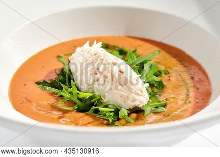Summer Spanish soup gazpacho with crab meat and rucola isolated on white background. Delicious cold tomato soup with crab. Clean eating for diet.Healthy food in restaurant menu. Crab gazpacho
