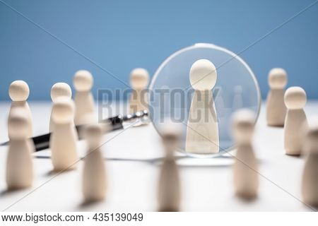 Recruitment and job search magnifying glass with wooden people concept for human resources and choosing the right people