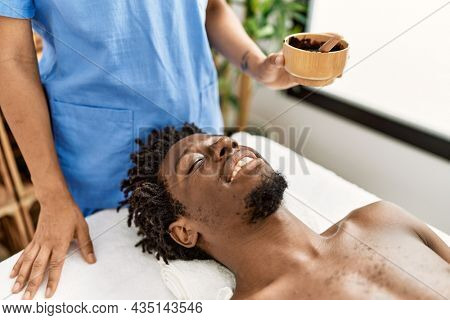 African american man reciving facial treatment at beauty center.