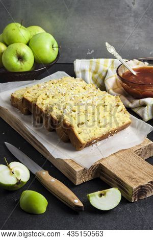 Sliced Apple And Coconut Oaf Cake On Wooden Cutting Board On Dark Background