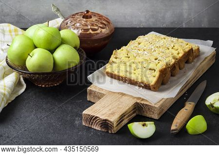Sliced Apple And Coconut Oaf Cake On Wooden Cutting Board On Dark Background
