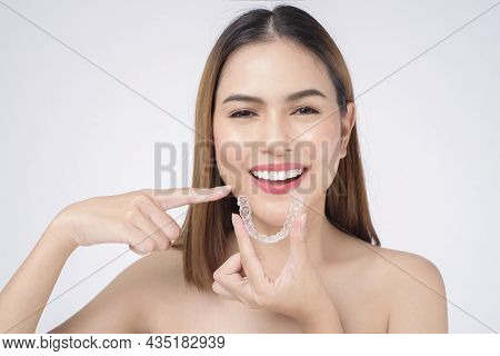 Young Smiling Woman Holding Invisalign Braces In Studio, Dental Healthcare And Orthodontic Concept