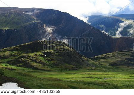 Dawn In The Altai Mountains At The Karagem Pass In Summer, Huge Rocky Mountains With Light Clouds Be