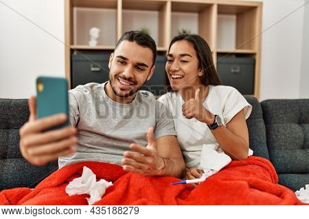 Young latin ill couple having medical teleconsultation using smartphone at home.