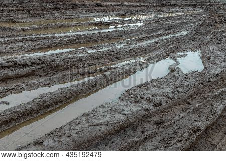 A Broken Rural Country Road. Puddles After Rain On A Dirt Road. Clay, Soil And Puddles At Cloudy Day