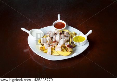 Salchipapa, Peruvian Grilled And Sliced Fresh Pork Sausage, Potato Fry On Black Background.