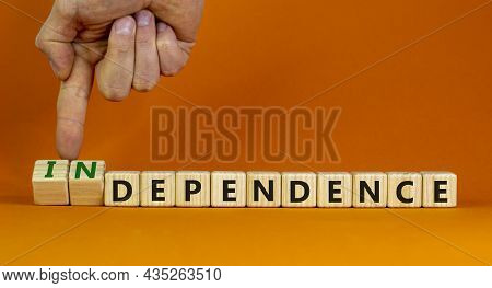 Dependence Or Independence Symbol. Businessman Turns Cubes And Changes The Word 'dependence' To 'ind