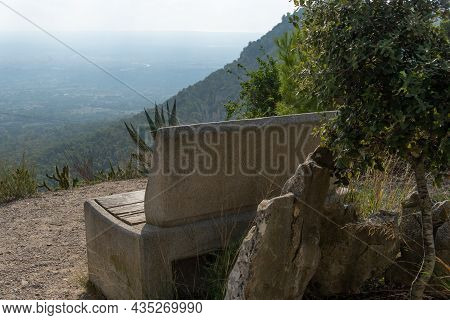 Stone Bench In Front Of A Mountanious Mediterranean Landscape At Sunset, On The Island Of Mallorca, 