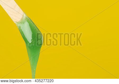 Wooden Spatula With Hot Depilatory Wax On Yellow Background. Space For Text