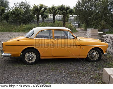 Stekene, Belgium, September 25, 2021, Side With Chrome Hubcaps Of An Orange Oldtimer Volvo 122s