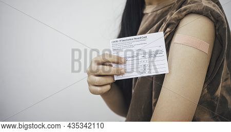 Woman Holding Down Her Shirt Sleeve And Showing Her Arm With Bandage After Receiving Vaccination.