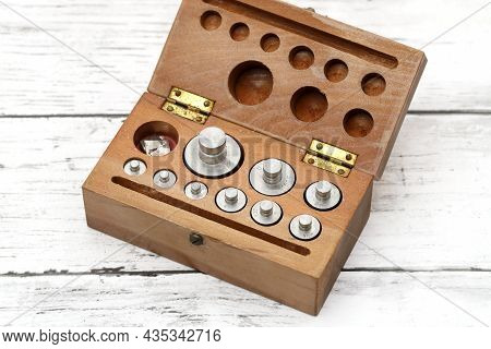 Set Of Metal Weights For Scales On The White Wooden Table