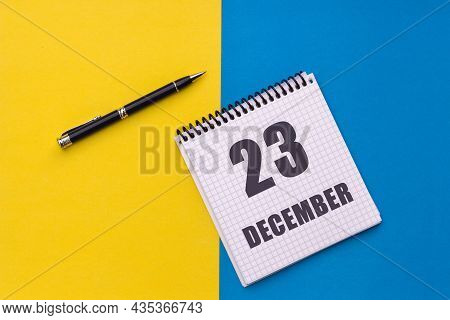 December 23th. Day 23 Of Month, Calendar Date. Notebook With A Spiral And Pen Lies On A Yellow-blue 