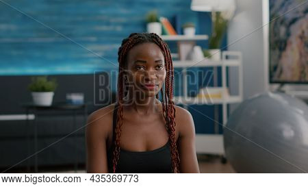 Black Woman Trainer Sitting In Lotus Position On Yoga Mat On Floor With Closed Eyes Meditating Durin